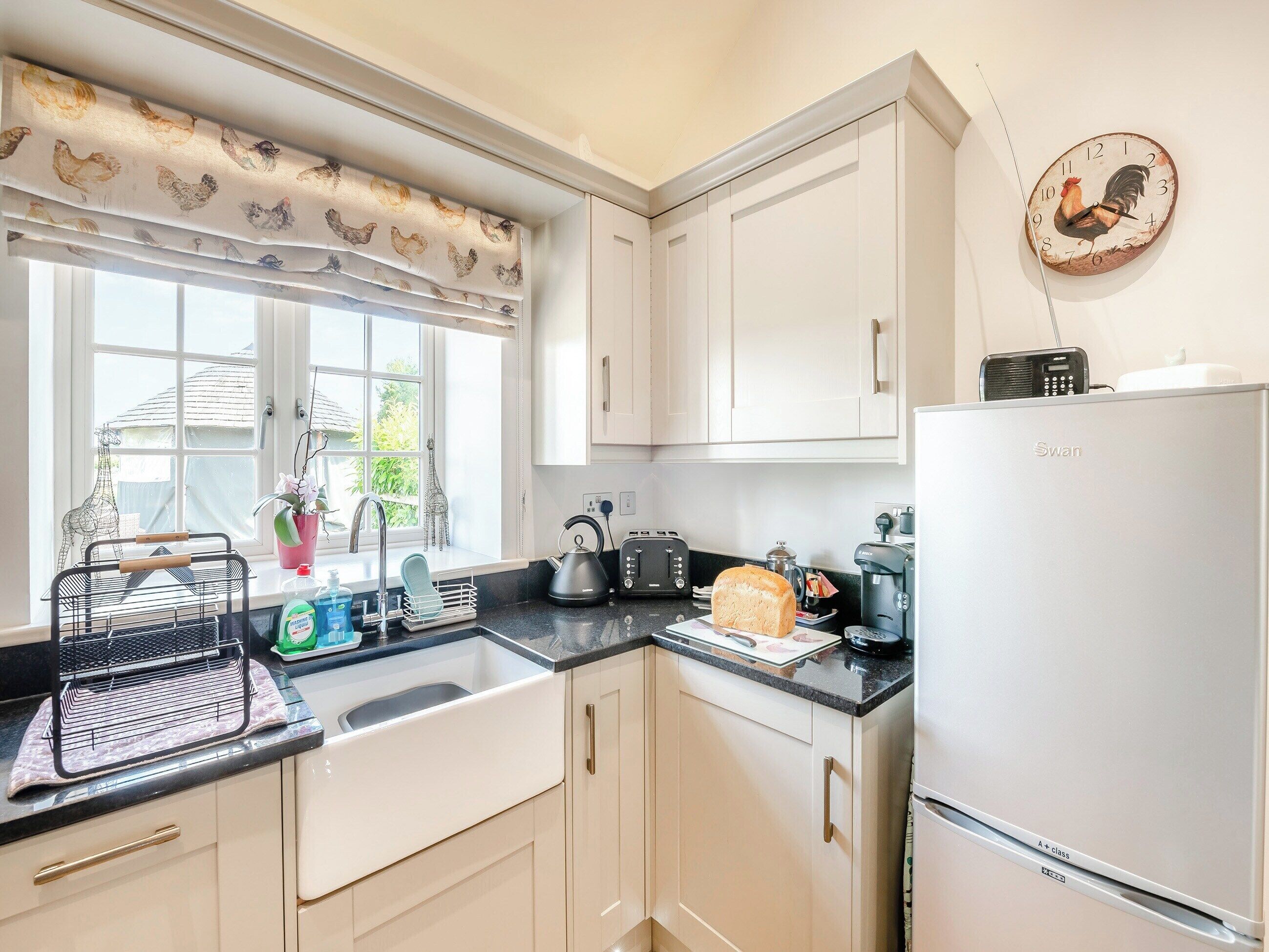A kitchen with white cabinets, a black countertop, a toaster, a kettle, and a refrigerator.