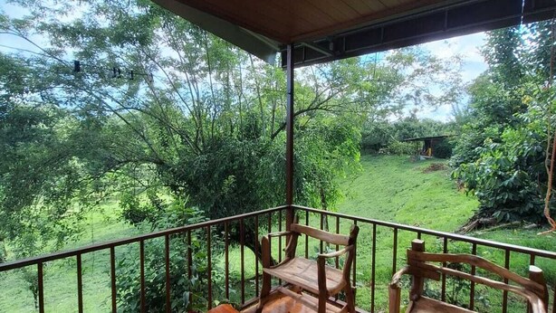 A wooden deck with a table and chairs, overlooking a lush garden. - Cabaña Refugio, located in the middle of nature. (La Fortuna)