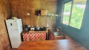 A compact kitchen with wooden cabinets, a refrigerator, a microwave, and a sink. - Cabaña Refugio, located in the middle of nature. (La Fortuna)