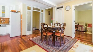 Un comedor con una mesa y sillas de madera, una cocina con armarios blancos y un reloj en la pared.