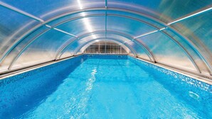 Una piscina interior con techo de cristal y suelo de baldosas.