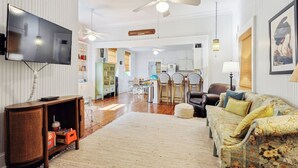 Un salon spacieux équipé d’un téléviseur à écran plat, d’un ventilateur de plafond et d’une grande fenêtre.