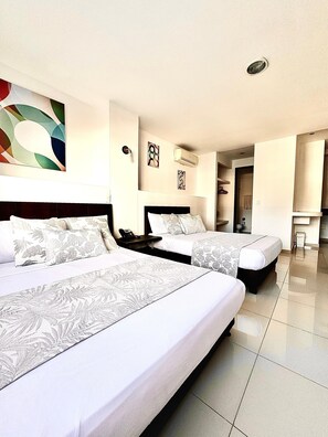 A hotel room with two beds, a large abstract painting on the wall, and a bathroom visible through an open door.