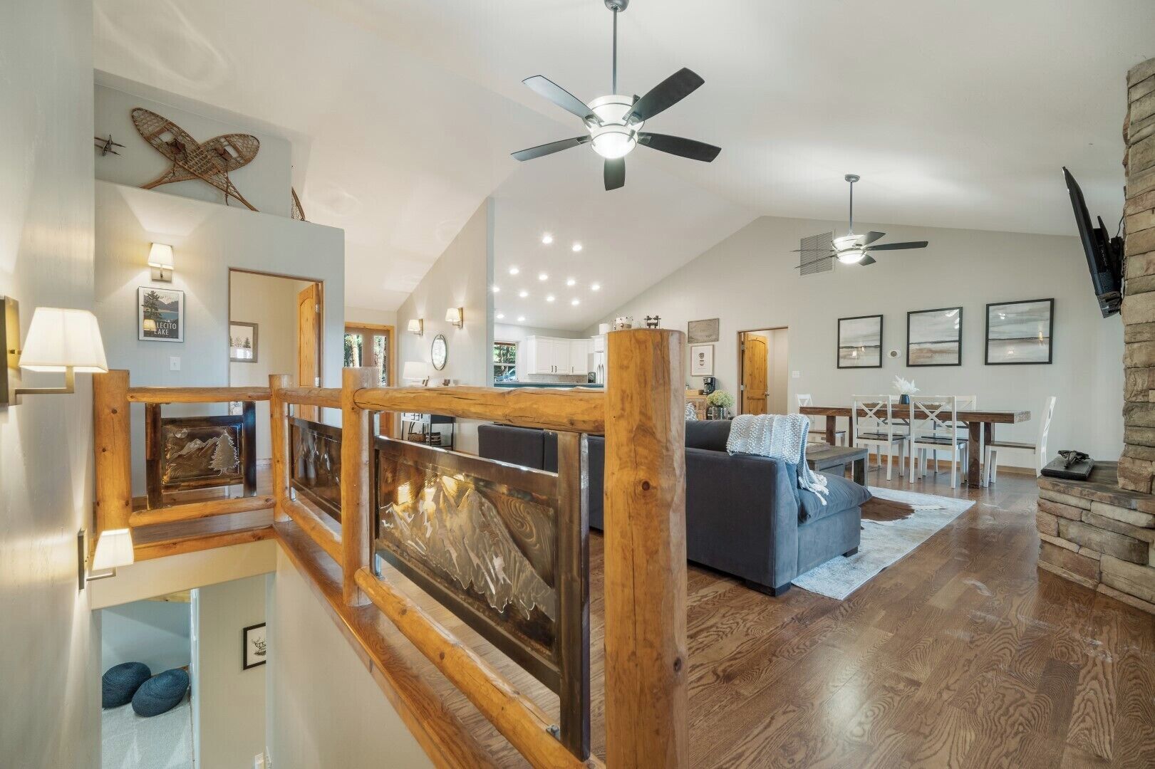 Un vaste espace de vie agrémenté d’un escalier en bois, d’un ventilateur de plafond et d’un coin repas avec une table et des chaises.