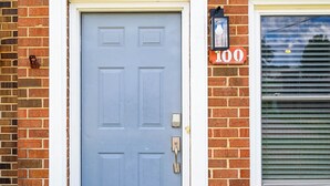 A blue door with a keypad lock, a mailbox, and a window with blinds.
