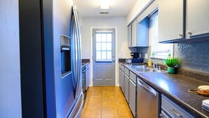A modern kitchen with stainless steel appliances, a granite countertop, and a potted plant.
