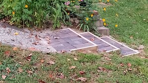 Ein Garten mit verschiedenen Blumen und zwei weißen Plastikstühlen.
