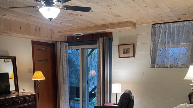 Ein Hotelzimmer mit Bett, Schreibtisch, Stuhl, Deckenventilator und einem Fenster mit Vorhängen.