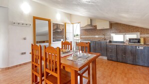 Eine kompakte Küche mit Essbereich, ausgestattet mit einem Holztisch, Stühlen, einer Ziegelrückwand und einer Mikrowelle.