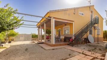 A two-story building with a covered patio area, outdoor seating, and a staircase leading to the upper floor.
