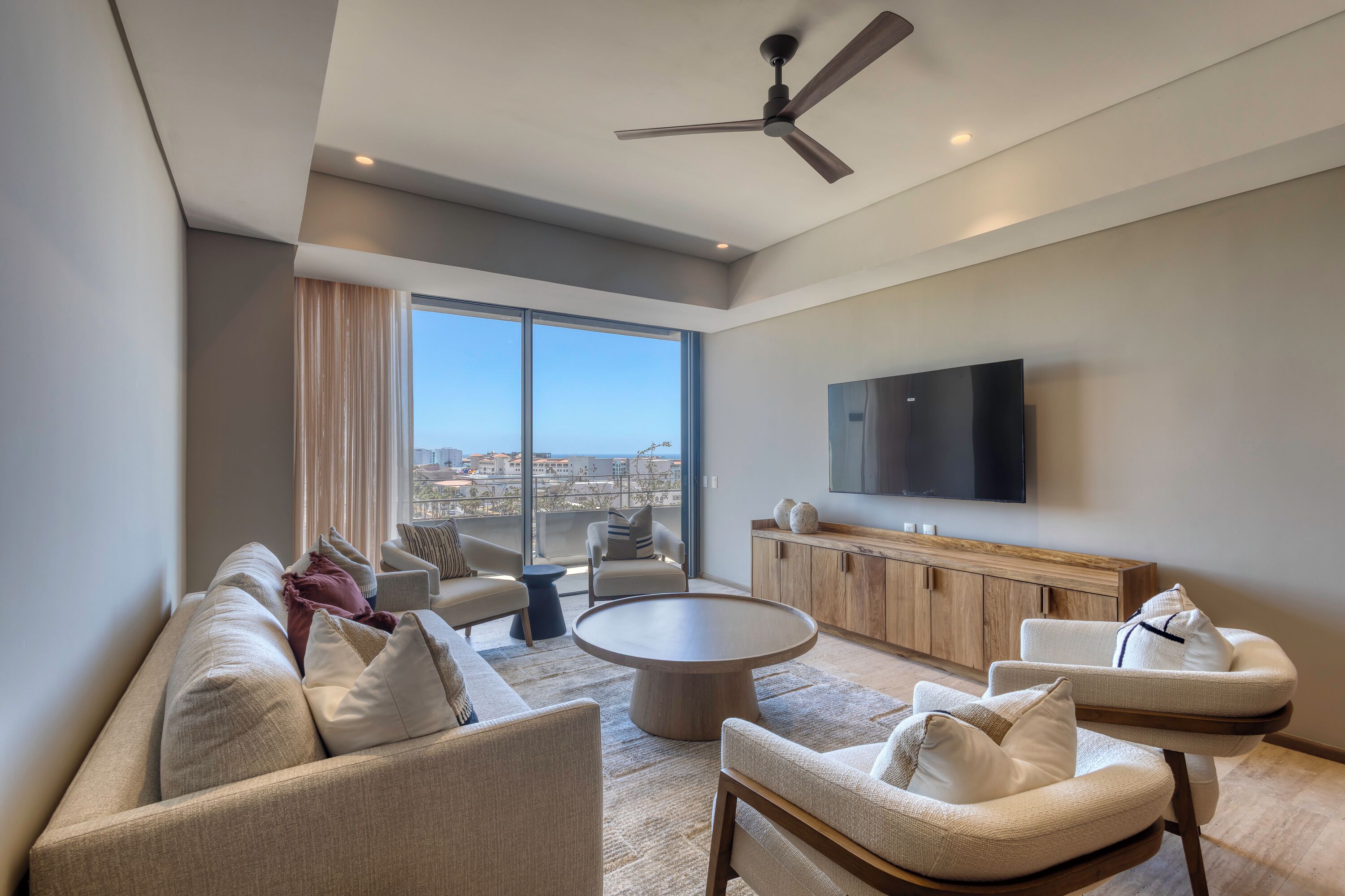 A modern living room with a sofa, chairs, a coffee table, and a TV.