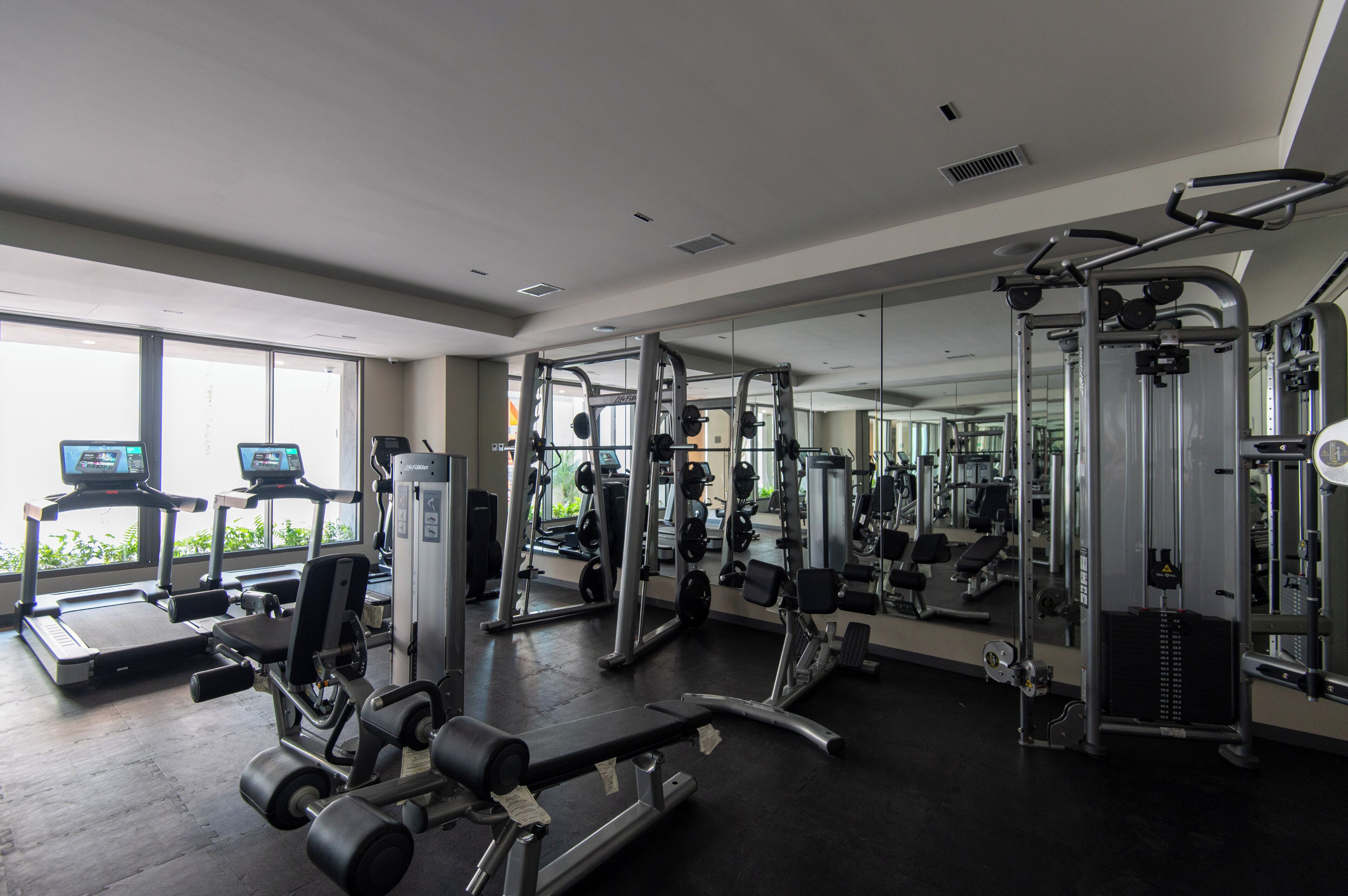 A gym with treadmills, weight machines, and a mirrored wall.