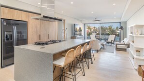 Une cuisine moderne dotée d’un grand îlot central, de tabourets de bar et d’un réfrigérateur encastré.