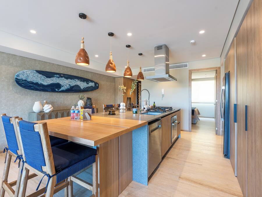A modern kitchen with a wooden island, pendant lighting, and a large decorative piece on the wall.