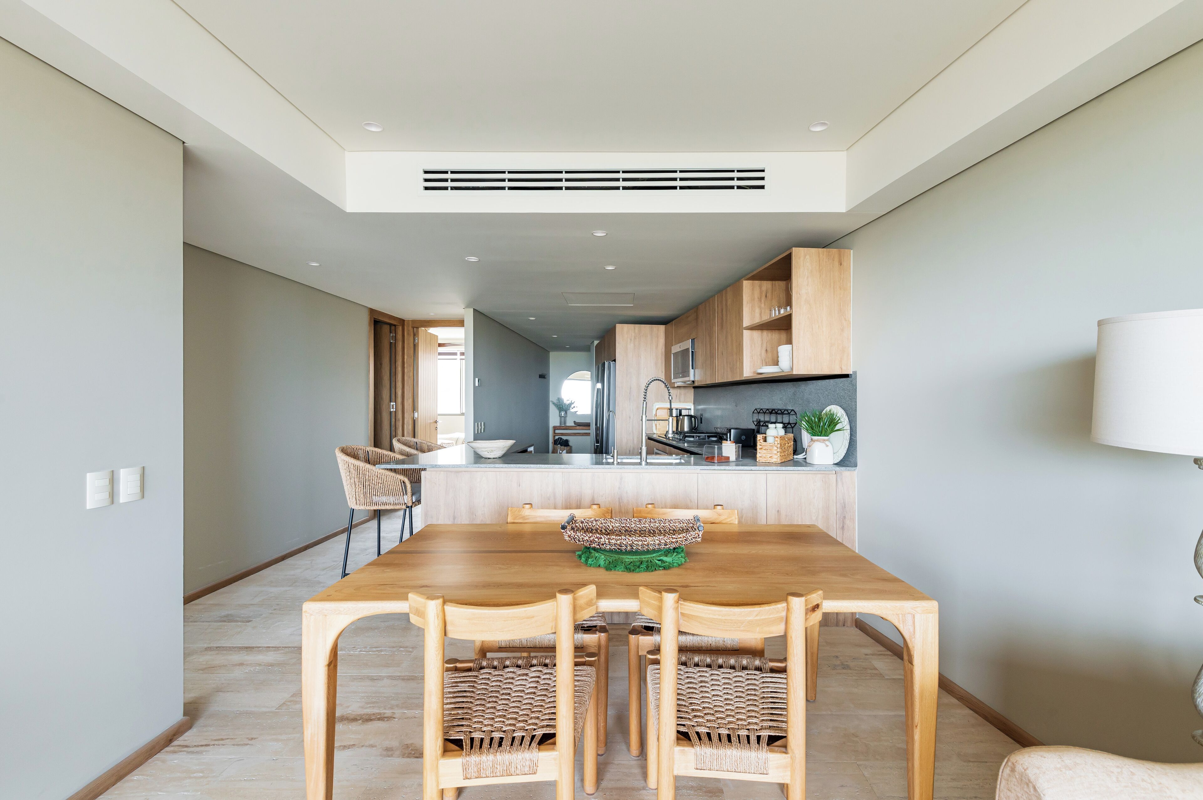 Een moderne keuken met houten kastjes, een centraal eiland en een eethoek met een houten tafel en stoelen.