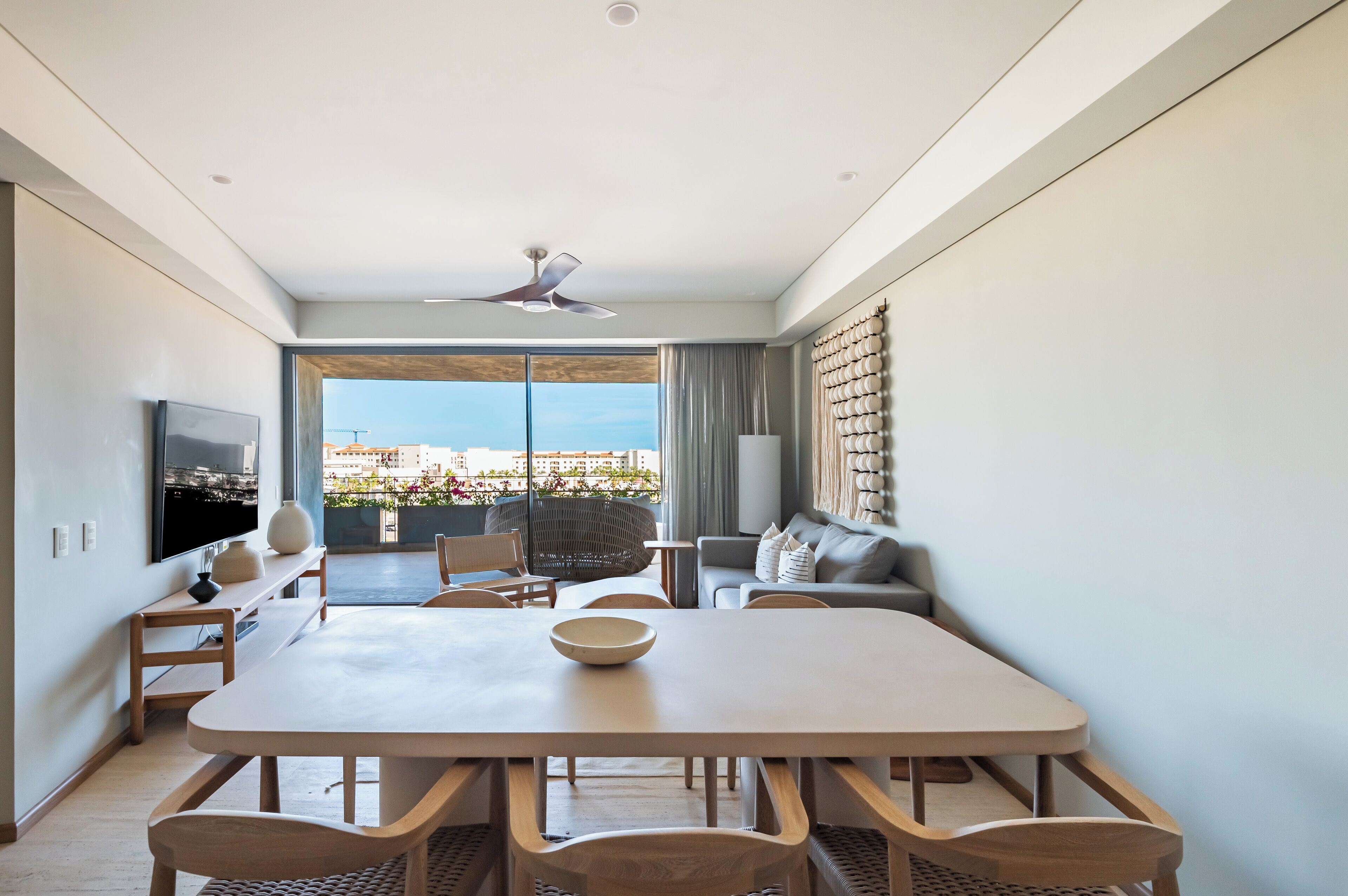 Una sala de estar moderna con un comedor amplio, asientos cómodos, un televisor de pantalla plana y vistas de la ciudad a través de grandes ventanales.