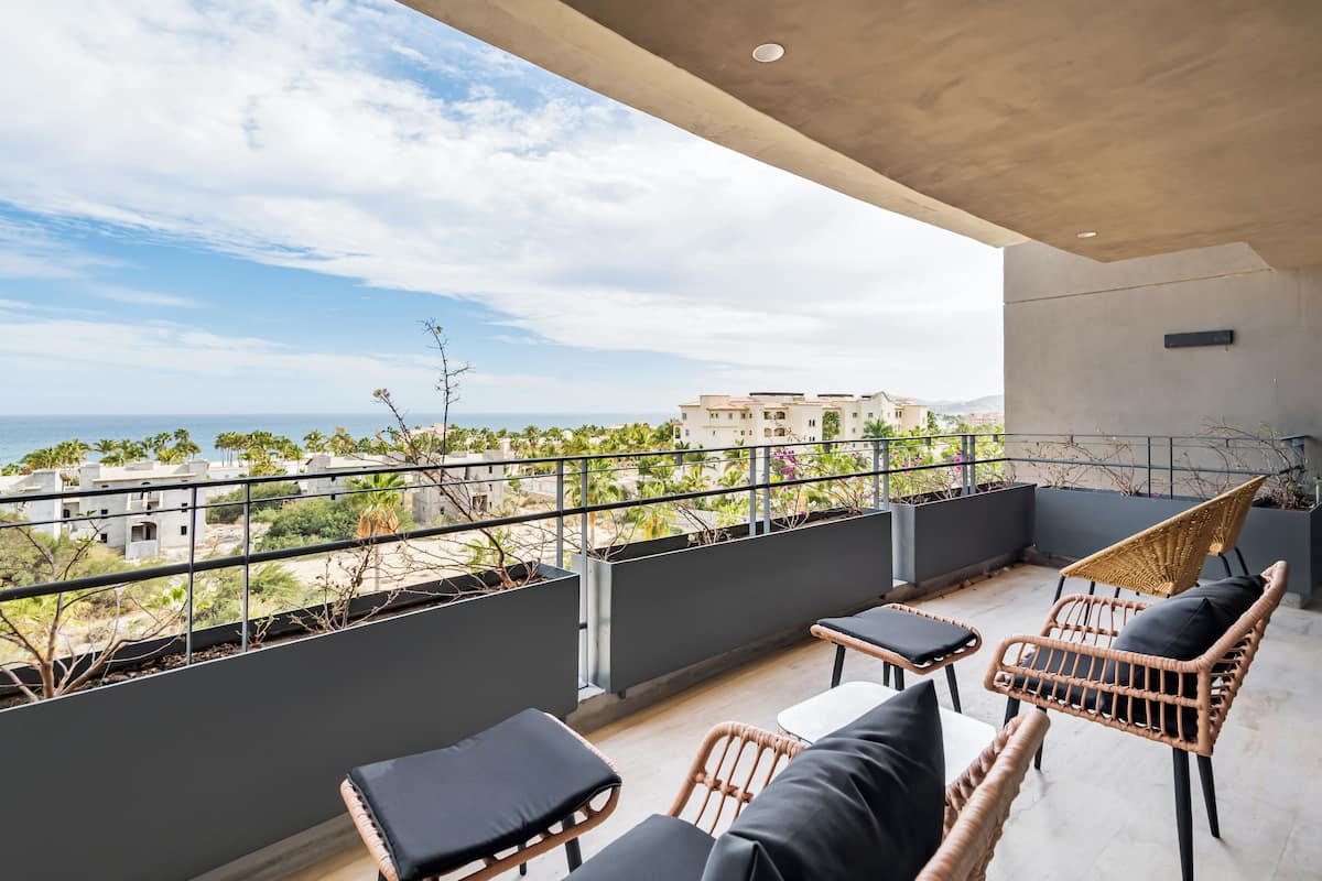 A balcony with wicker furniture and a view of the sea.