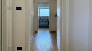 Ein Korridor mit Holzboden, der zu einem Zimmer mit Fenster und einer eingebauten Bank führt.