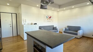Eine moderne Küche mit Kochinsel, Holzboden und einem grauen Sofa im Wohnbereich.