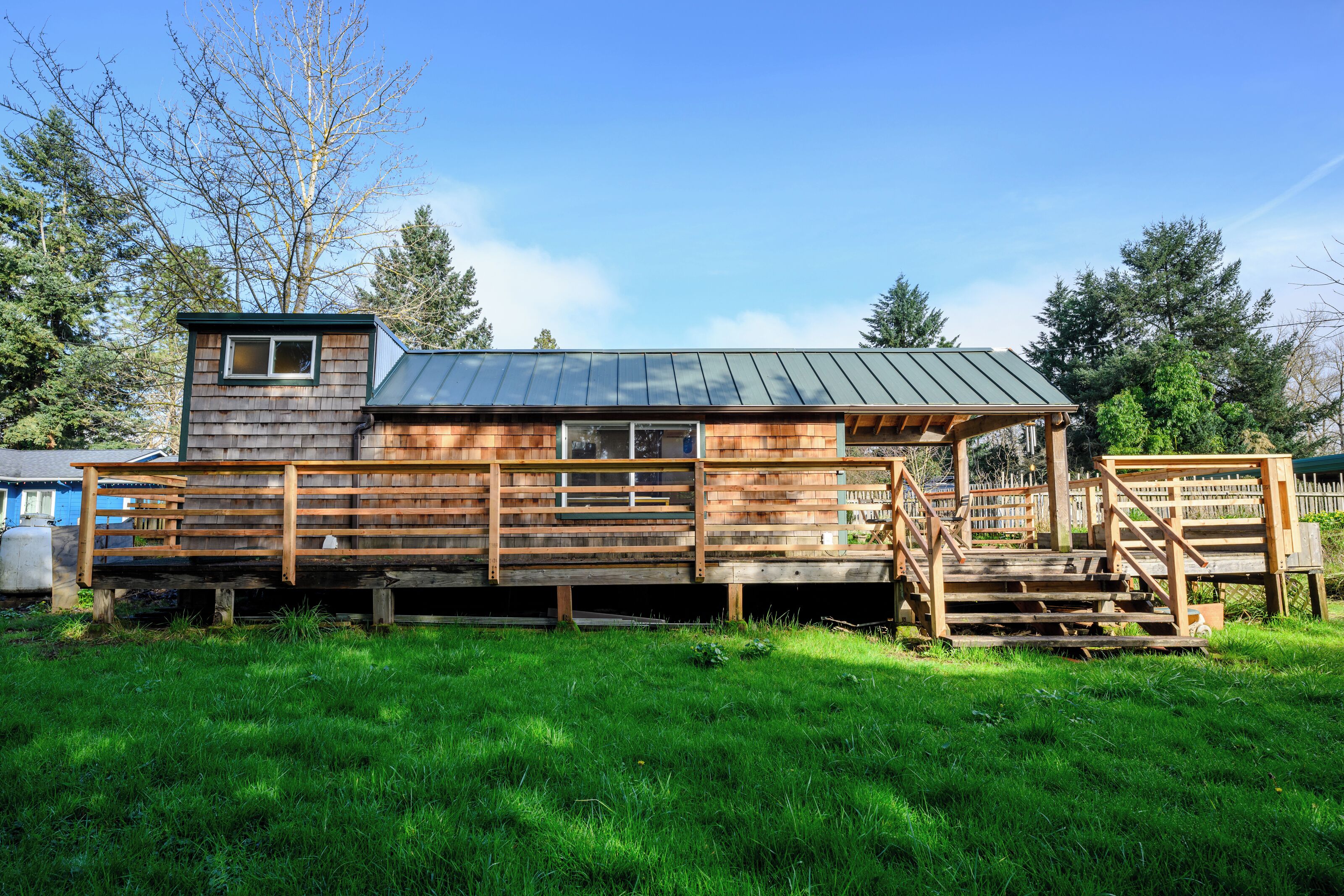 A wooden cabin with a metal roof, a small window, and a porch with steps.
