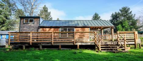 A wooden cabin with a metal roof, a small window, and a porch with steps.