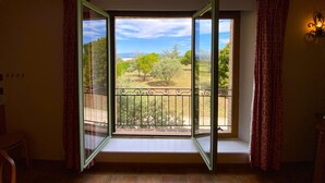 A room with a large open window, a balcony with a metal railing, and a view of a landscape with trees and a clear sky. - 04B3: Beautiful T3 in the heart of lavender - pool (Brunet)