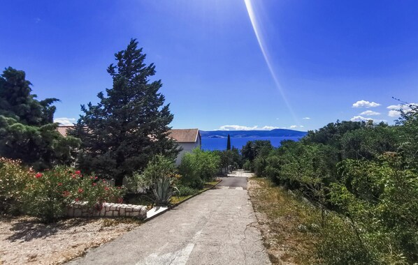 Un camino pavimentado que lleva a un edificio con vistas al mar y montañas al fondo.