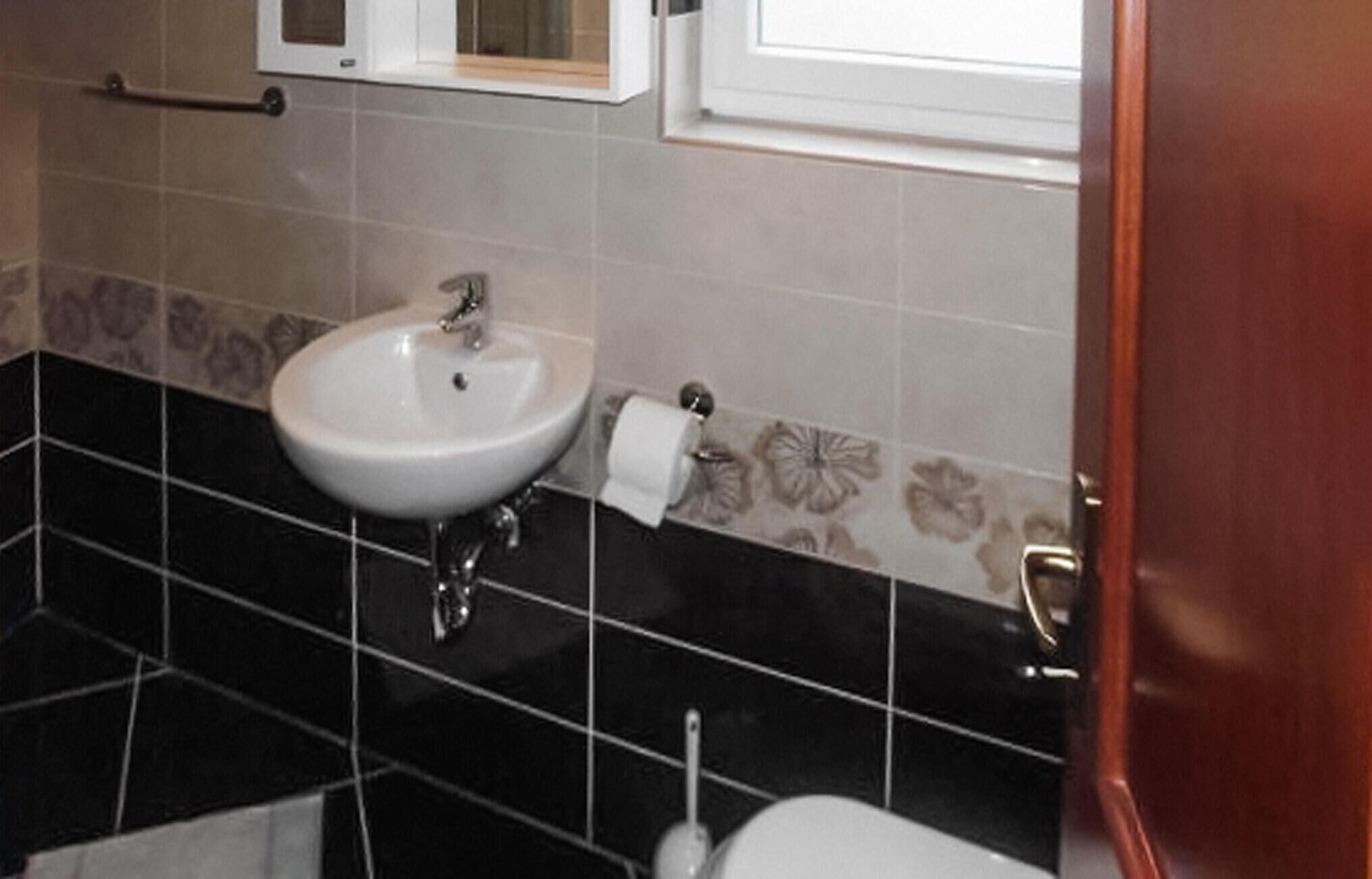 A bathroom with a white sink, black tiled floor, and a toilet.