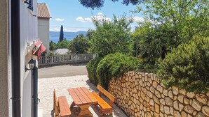 A stone wall, wooden bench, and picnic table in a sunny outdoor area. - 2 bedroom beautiful apartment in Novi Vinodolski (Novi Vinodolski)