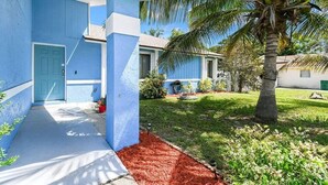A blue house with a front door, a palm tree, and a well-maintained lawn. - BR Tropical Oasis in Port St Lucie (Port Saint Lucie)