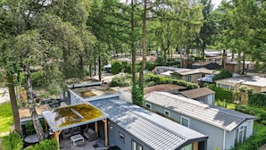 A modern house with a flat roof, large windows, and a patio area with outdoor furniture.