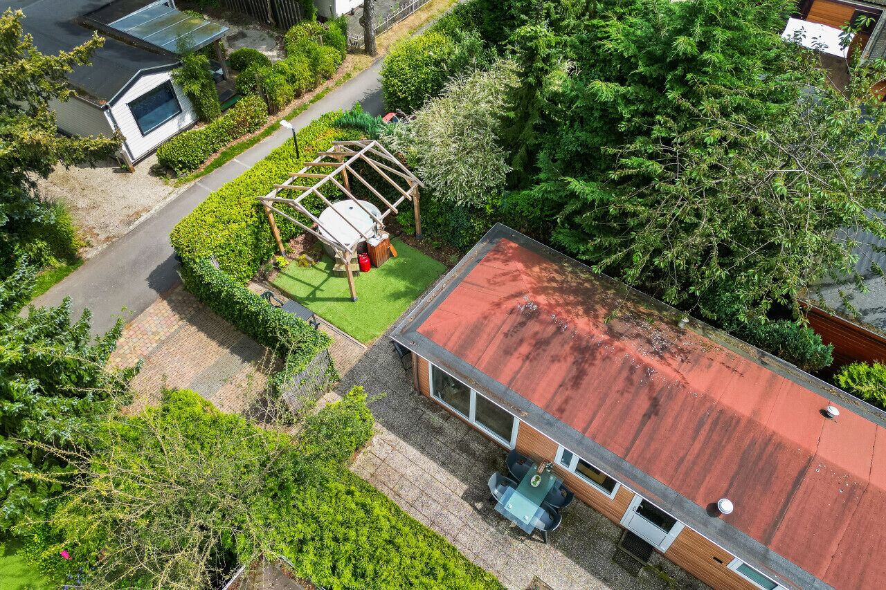 A residential property with a red roof, a covered outdoor area, and a garden.