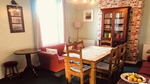 Una sala de estar acogedora con una mesa de comedor de madera, un sofá rojo y una pared de ladrillo.