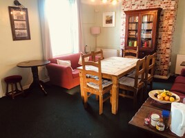 Una sala de estar acogedora con una mesa de comedor de madera, un sofá rojo y una pared de ladrillo.