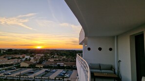 A balcony with a view of a sunset over a residential area.