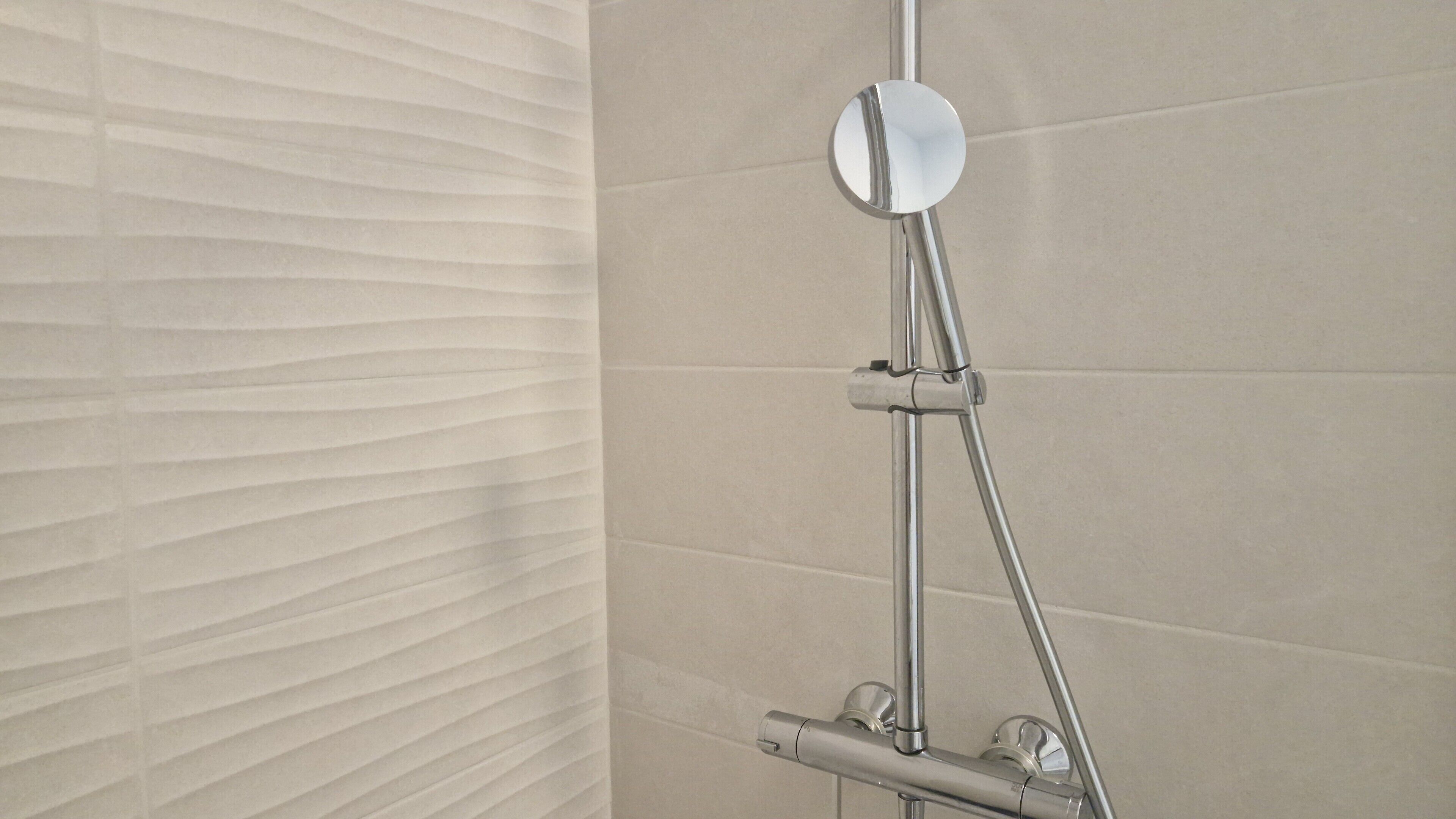 A bathroom with a shower, a mirror, and a towel rack.
