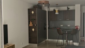 A modern living room with a round gold ottoman, a grey sofa, and a striped rug. - Archipelago Garden Side (Valras-Plage)