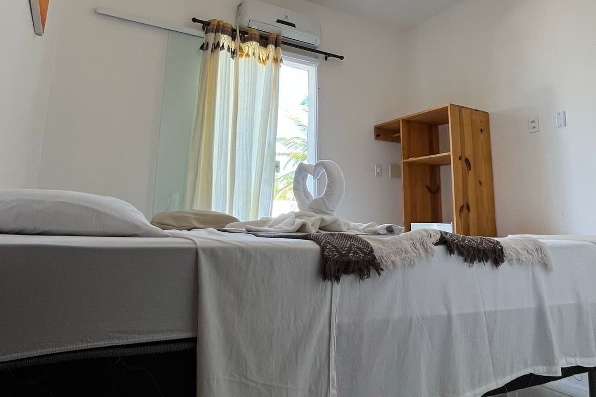 Ein Schlafzimmer mit einem Bett, einem Nachttisch, einem Spiegel, einer Klimaanlage, einem Holzschrank und einer Deckenleuchte.