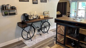 Eine Küche mit einem Fahrrad, einer Kaffeemaschine und einem Schild mit der Aufschrift 'Willkommen in der Küche'.
