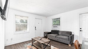 Un salon avec un canapé gris, une table basse en bois et un tapis.