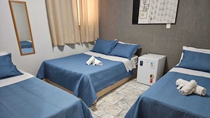 A hotel room with three single beds, each with blue bedding and white pillows. There is a small white refrigerator on one side of the room. - ALLIANCE HOTEL (Bauru)