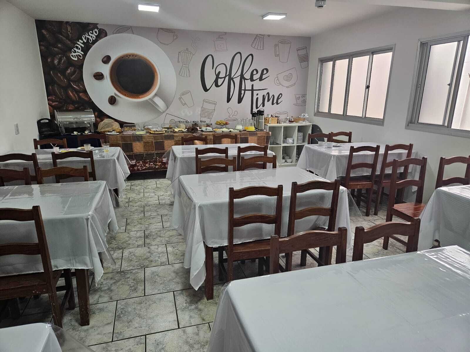 Un restaurant avec des tables et des chaises, un coin café et un mur sur lequel est écrit « Coffee Time ».