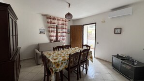 A dining area with a table set for four, a sofa, a cabinet, and a door leading outside.