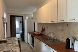 Eine moderne Küche mit Holzschränken, einer Edelstahlspüle und einer Kaffeemaschine.