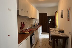 A compact kitchen with wooden cabinets, a built-in oven, and a dining table with a placemat.