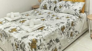 A neatly made bed with a floral bedspread, two pillows, and a bedside table with a lamp. - Relax and comfort in the center of Naples (Napoli)