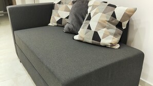 A grey sofa with patterned cushions against a white wall, on a tiled floor. - Relax and comfort in the center of Naples (Napoli)