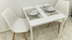A white dining table with two chairs, each with wooden legs, set with plates, glasses, and cutlery. - Relax and comfort in the center of Naples (Napoli)