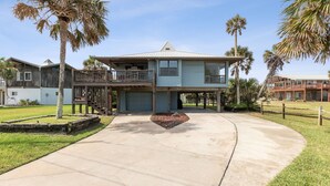 A two-story house with a balcony, a garage, and a well-maintained lawn. - Pet friendly house across from the ocean, 30 day minimum stay (Fernandina Beach)