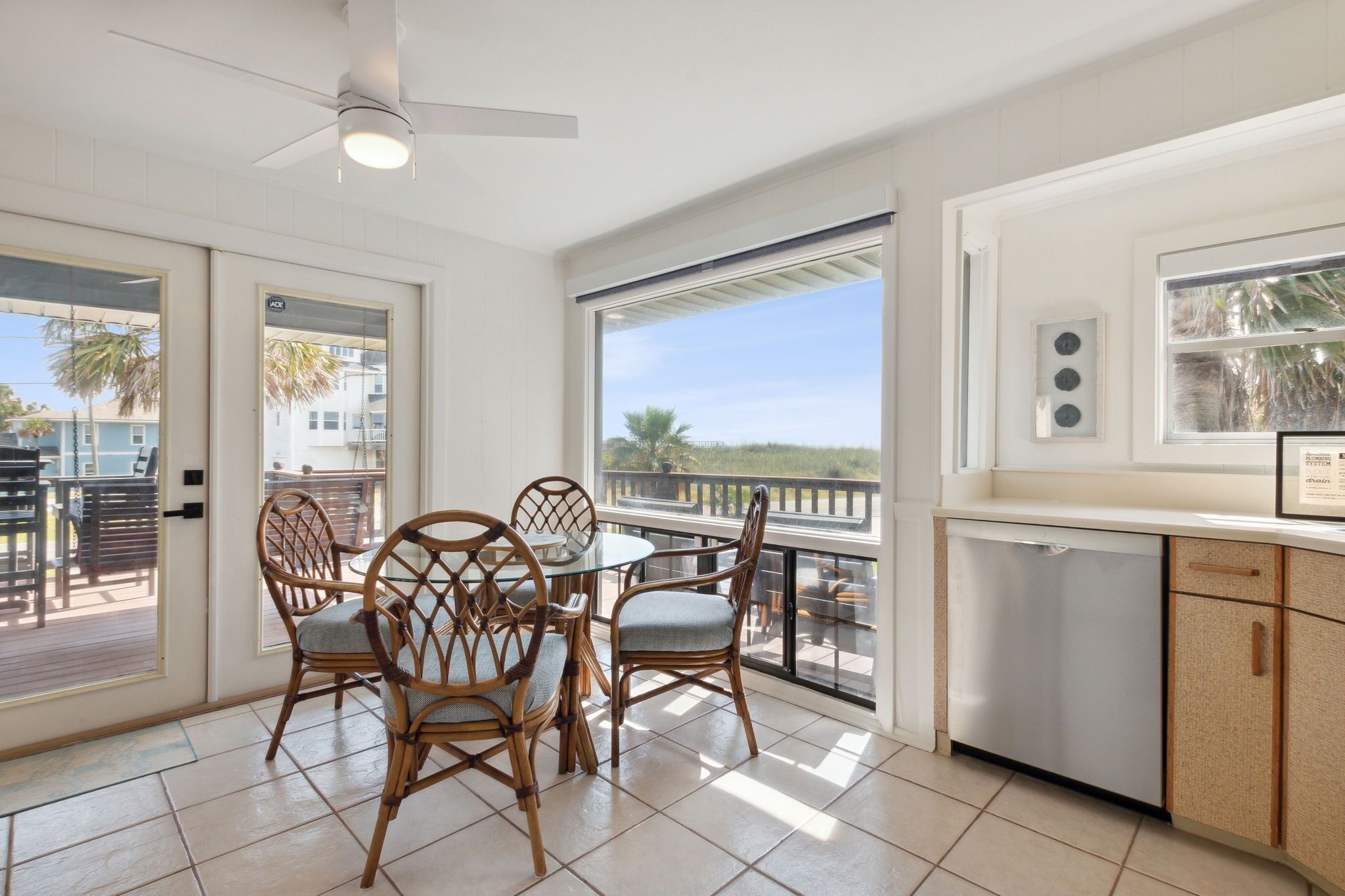 A spacious balcony with a dining area, a ceiling fan, and a view of the ocean.